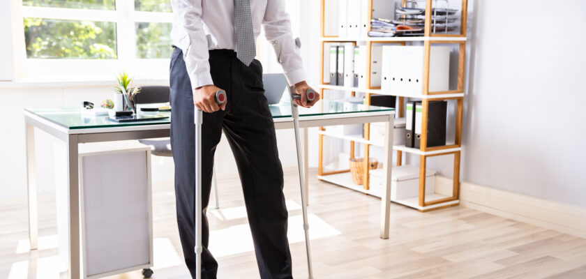 Disabled Businessman With Crutches Standing In Office