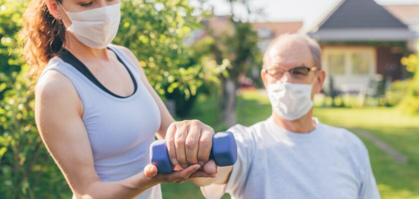 A woman providing in-home elder care for her aging father helps him work out and stay healthy.