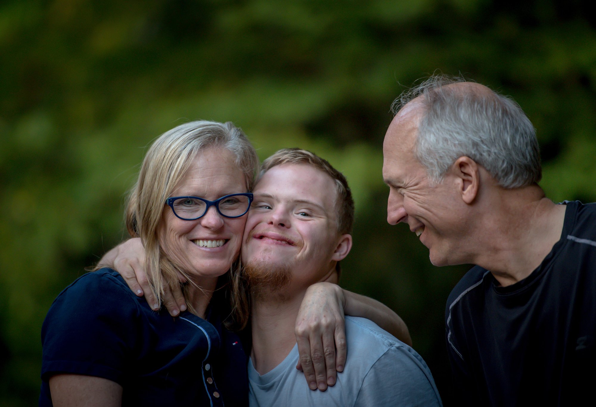 A man and woman hug their son. As his caregivers, they are more successful because they utilize the support of caregiving guides to make sure he has what he needs.